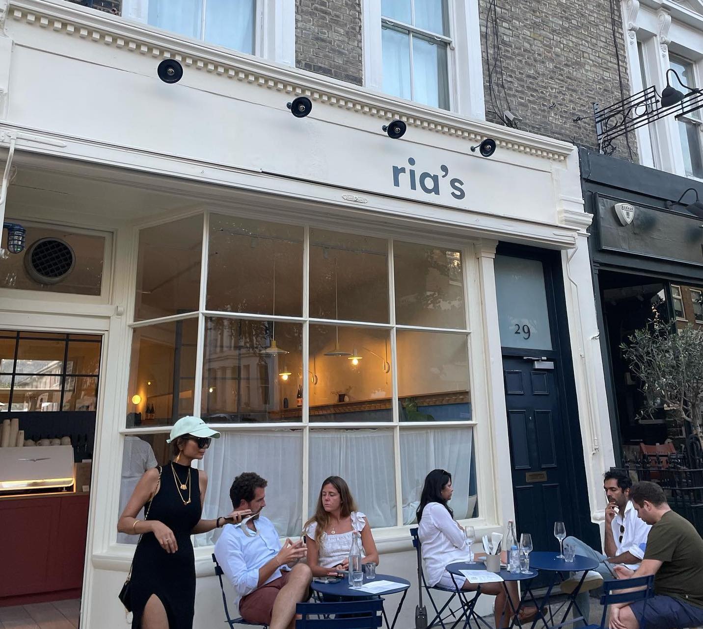 Storefront of Ria's with people sat outdoors in Notting Hill London