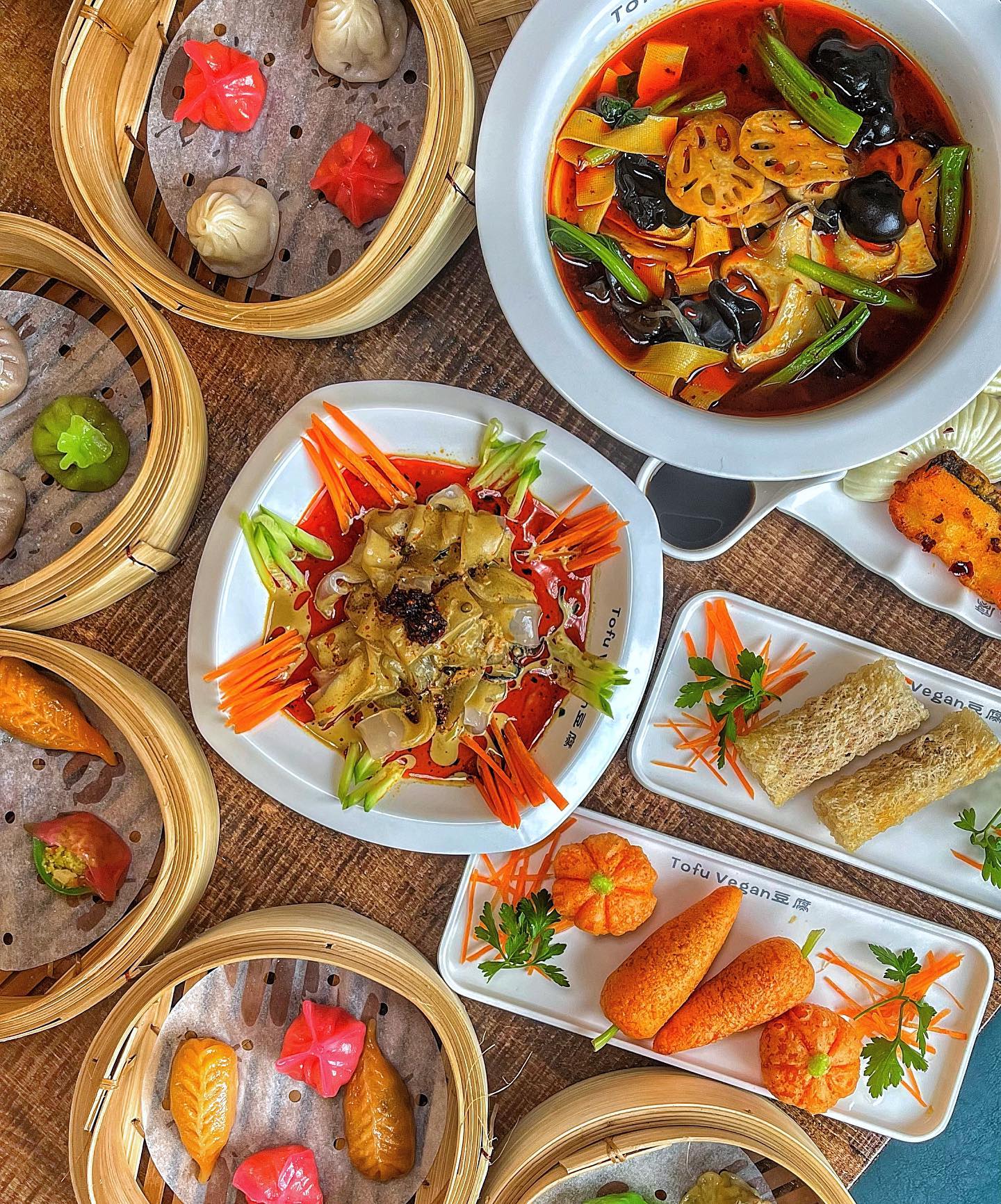 A table full of Chinese dishes, like vegan dumplings, mushrooms, and tofu.