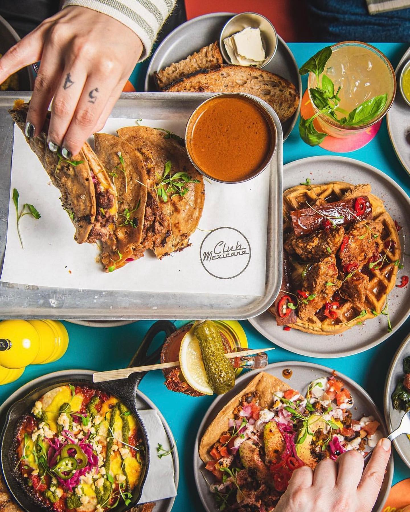 A large table full of Mexican dishes, like tacos, enchiladas, and margaritas.