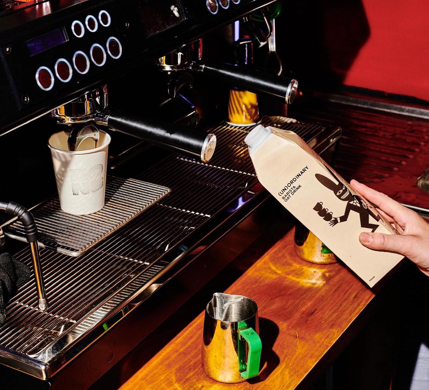 Coffee machine making espresso with barista holding oat milk at Rons Coffee House in Peckham London